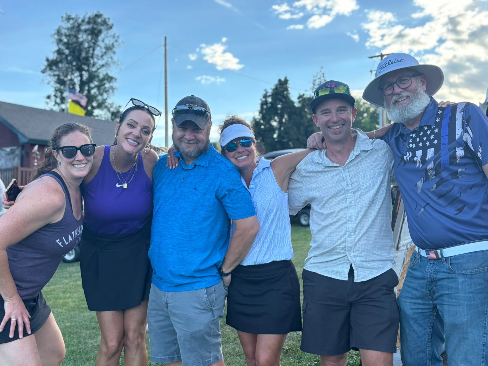 Faculty, alumni, and supporters gathered together outdoors after tournament play.